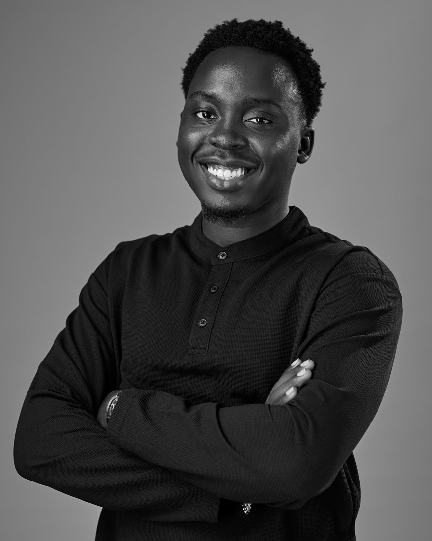Mosh smiling with his arms crossed, in a black-and-white portrait